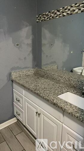 A bathroom with a granite countertop and white cabinets.