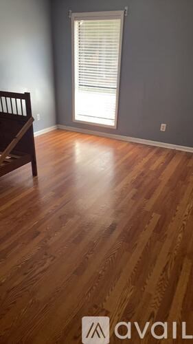 A room with wooden flooring and a window with blinds.