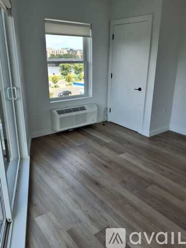 A room with a window overlooking a pool and a balcony.