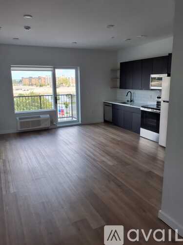 A spacious kitchen with dark wood floors and white appliances.