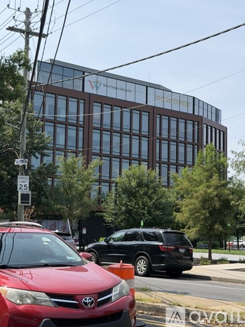 A red car is parked on the side of the road in front of a building with the sign "Walmart".