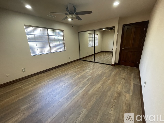 A room with a ceiling fan and wooden flooring.