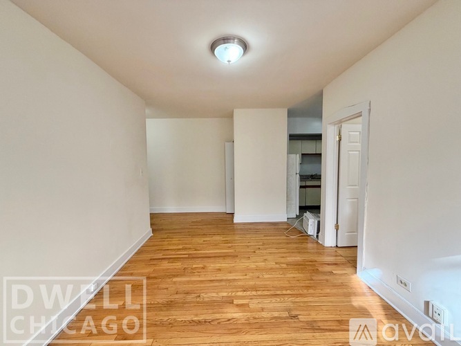 A spacious room with wooden flooring and white walls.