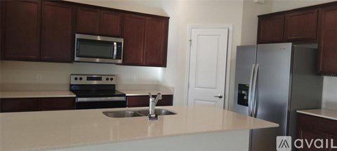 A kitchen with brown cabinets and a stainless steel refrigerator.