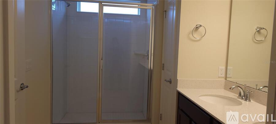 A bathroom with a sink, mirror, and shower.