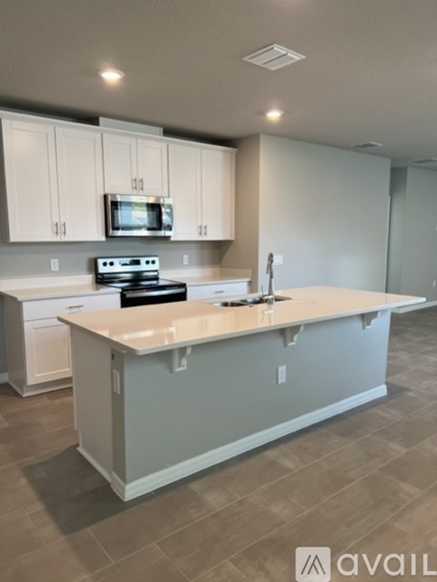 A kitchen with a white island and a microwave above it.