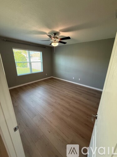 A room with a ceiling fan and wooden flooring.