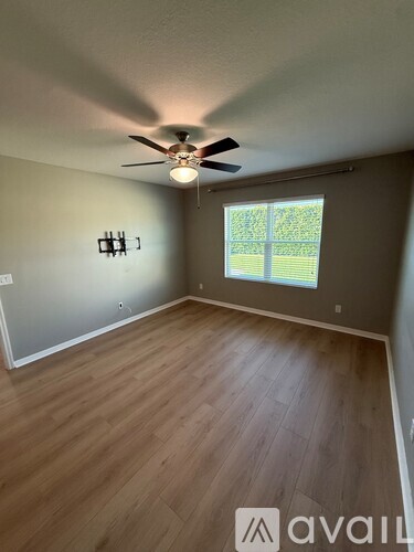 A room with a ceiling fan and wooden flooring.
