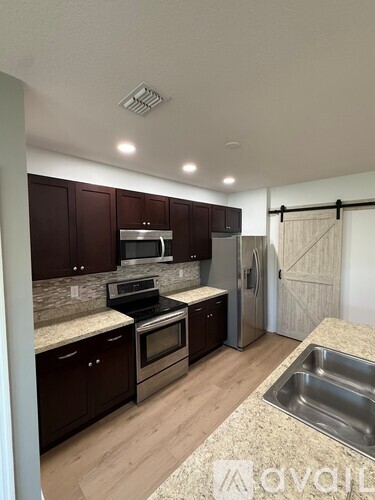 A kitchen with dark brown cabinets and stainless steel appliances.