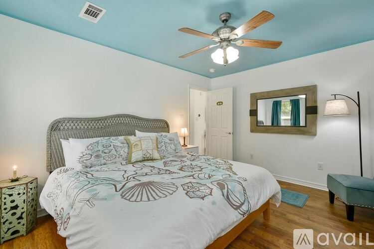 A bedroom with a bed, a ceiling fan, and a mirror on the wall.