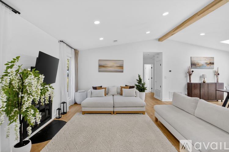 A living room with a white couch, a fireplace, and a painting on the wall.