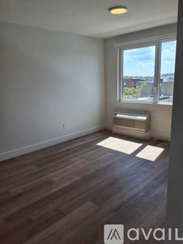 A room with wooden flooring and a window overlooking a cityscape.
