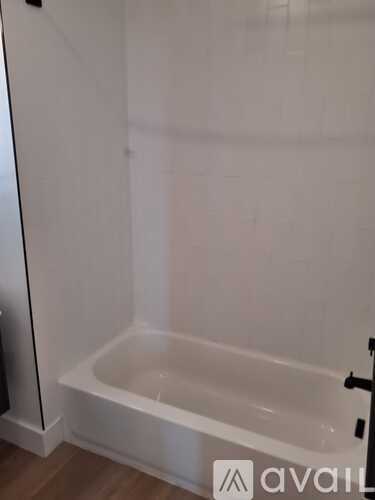 A white bathroom with a bathtub and a towel rack.