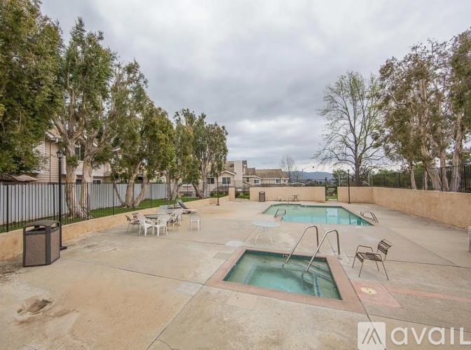 A pool area with a hot tub and chairs.