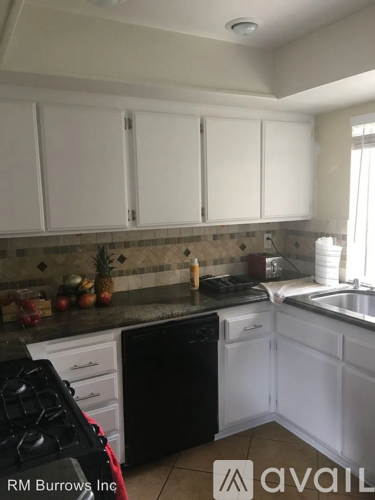A kitchen with white cabinets and a black dishwasher.
