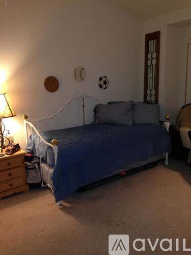 A bedroom with a blue bed and a lamp on a nightstand.
