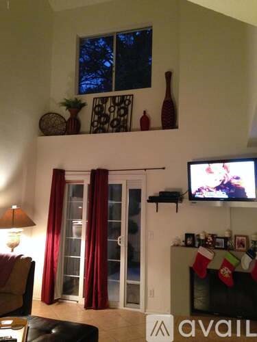 A living room with a television on the wall and a fireplace with stockings hanging.