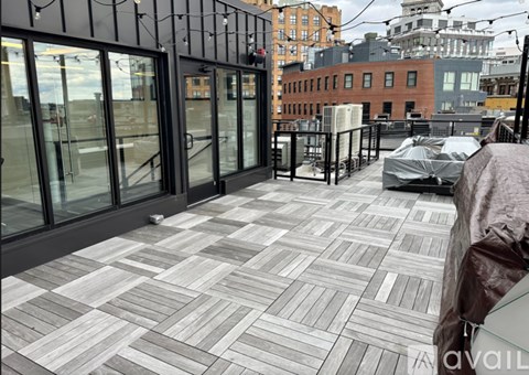 A rooftop patio with a grey tiled floor and glass walls.