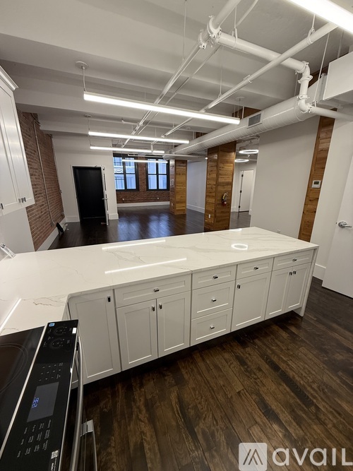 A large open office space with a long white desk and a black office chair.