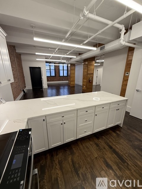 A large open office space with a long white desk and a black office chair.