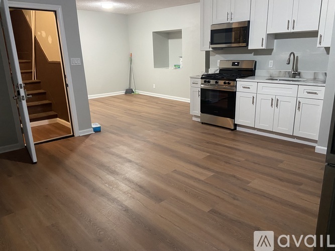 A kitchen with white cabinets and a wooden floor.