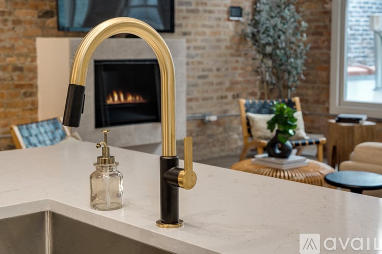 A kitchen with a gold faucet and a fireplace in the background.