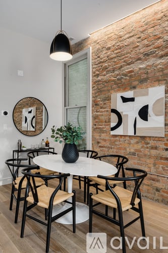 A white table with chairs and a plant on it in front of a brick wall.
