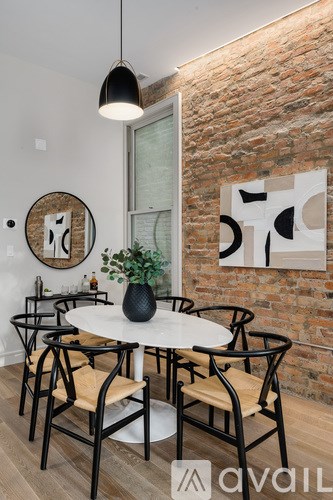 A white table with chairs and a plant on it in front of a brick wall.