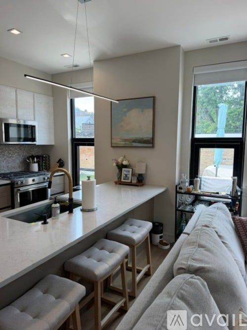 A kitchen with a white countertop and a grey couch.