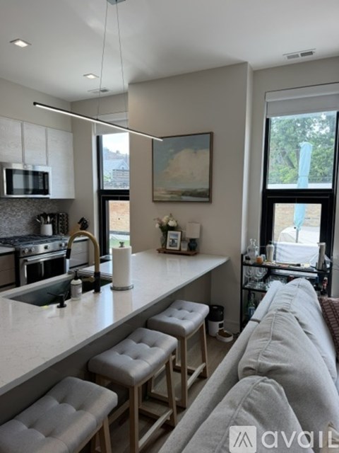 A kitchen with a white countertop and a grey couch.