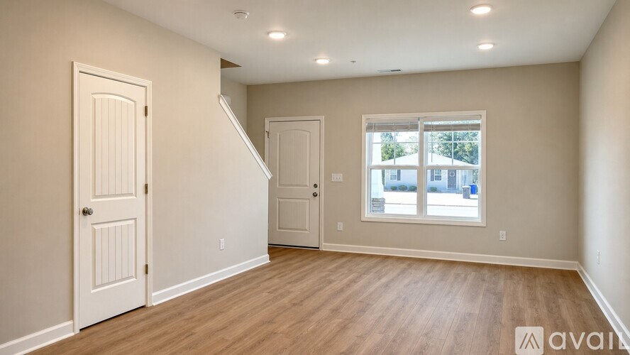 A spacious room with wooden floors and white walls.