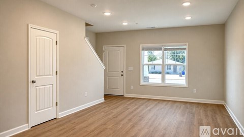 A spacious room with wooden floors and white walls.