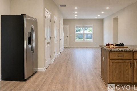 A kitchen with a black fridge and wooden cabinets.