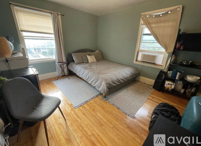 A bedroom with a bed, chair, and window.