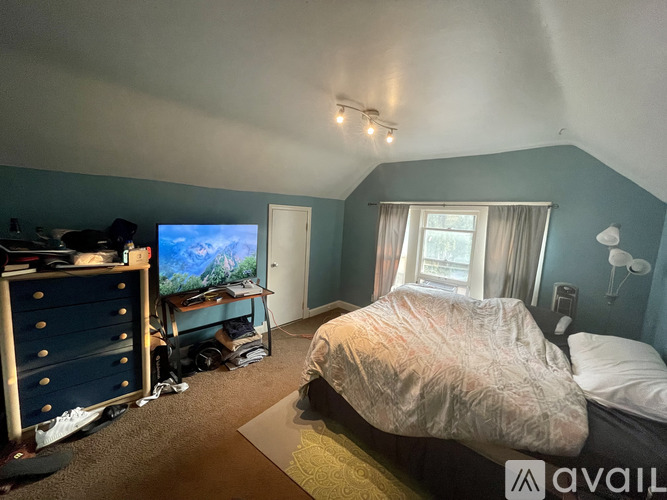 A bedroom with a bed, dresser, and a window.
