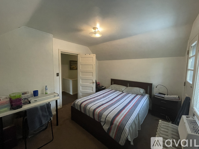 A bedroom with a bed, desk, chair, and window.