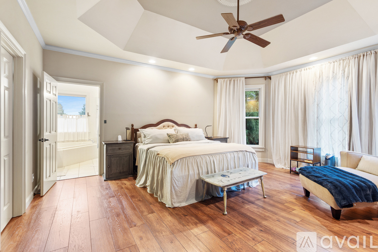 A bedroom with a large bed and a ceiling fan.