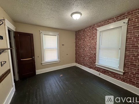 A room with a brick wall and a window with blinds.