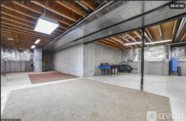 A spacious room with a high ceiling and exposed pipes.