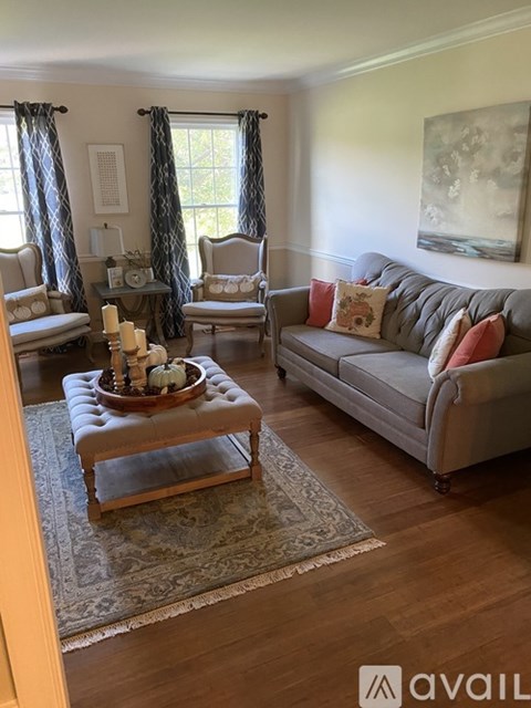 A living room with a grey couch, a wooden coffee table, and a large painting on the wall.