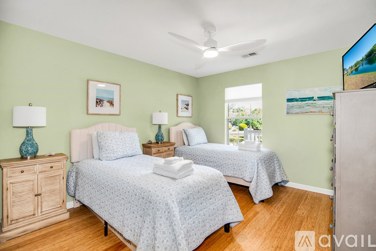 A bedroom with two beds and a ceiling fan.