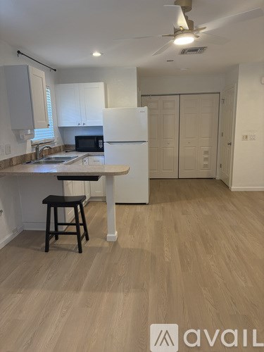 A kitchen with a white fridge and a bar stool.