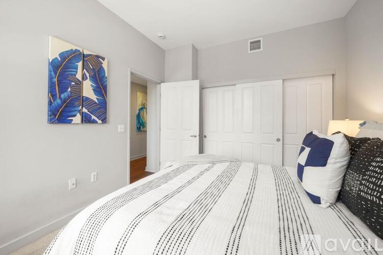 A bedroom with a large bed and a painting on the wall.