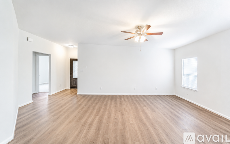 A spacious room with a ceiling fan and wooden flooring.