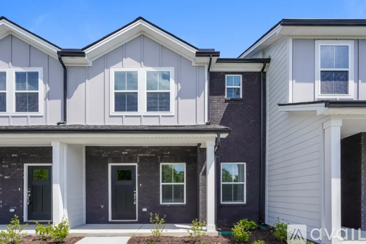 A modern two-story house with a front porch and multiple windows.