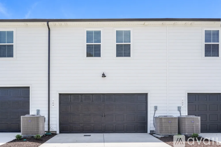 A white building with two garage doors and a black pipe on the side.