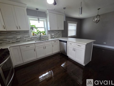 A kitchen with white cabinets and a wooden floor.