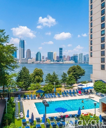 A pool area with chairs and umbrellas overlooking a city skyline.
