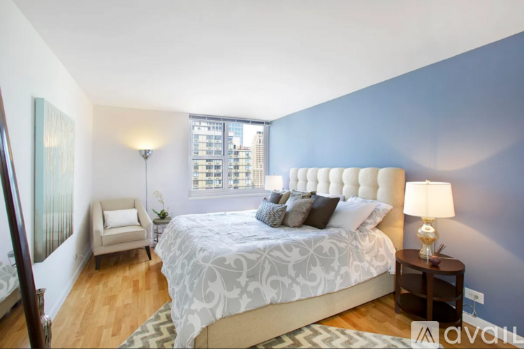 A bedroom with a large bed and a chair.