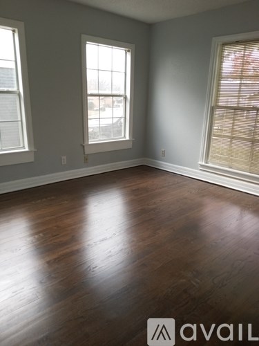 A room with wooden floors and two windows.